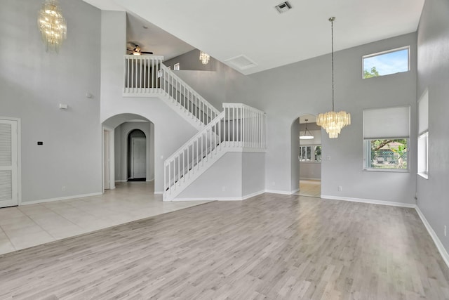 unfurnished living room with a towering ceiling, light hardwood / wood-style flooring, and a healthy amount of sunlight