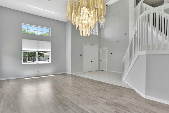 entryway featuring a notable chandelier, light wood-type flooring, and a towering ceiling