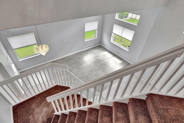 staircase featuring carpet, a chandelier, and a high ceiling