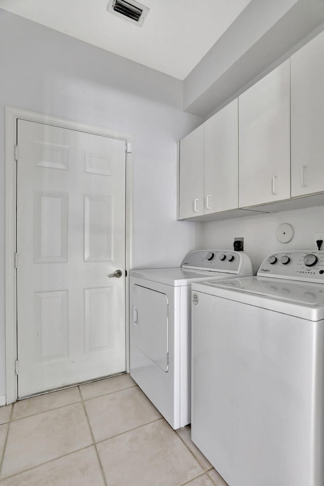 laundry area with light tile patterned floors, separate washer and dryer, and cabinets