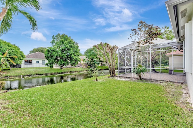 view of yard featuring a patio area, a water view, and a lanai