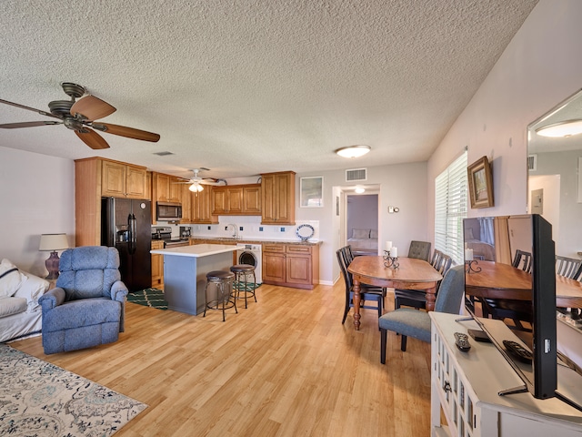 dining space with washer / clothes dryer, ceiling fan, a textured ceiling, and light hardwood / wood-style flooring