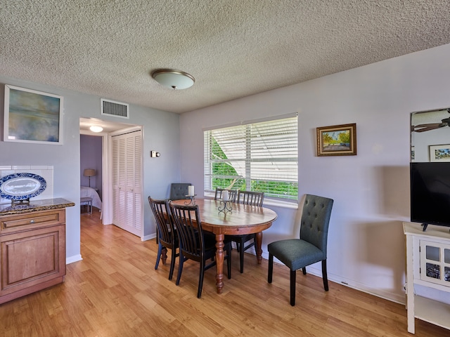 dining room with a textured ceiling, light hardwood / wood-style flooring, and ceiling fan