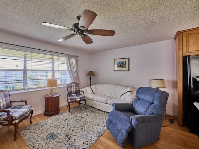 living room with light hardwood / wood-style flooring, a textured ceiling, and ceiling fan