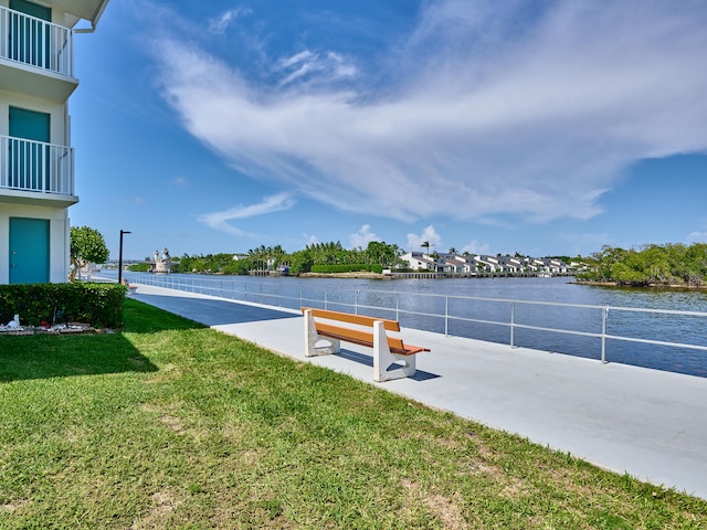 dock area featuring a balcony, a water view, and a lawn