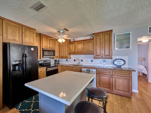 kitchen with tasteful backsplash, ceiling fan, a breakfast bar area, appliances with stainless steel finishes, and light hardwood / wood-style flooring