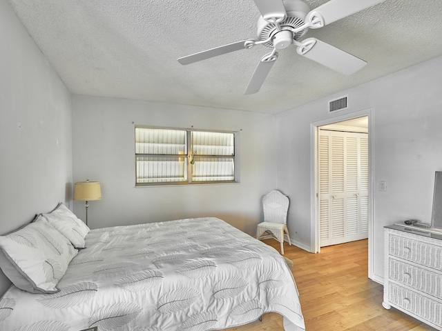 bedroom with a closet, a textured ceiling, ceiling fan, and light wood-type flooring