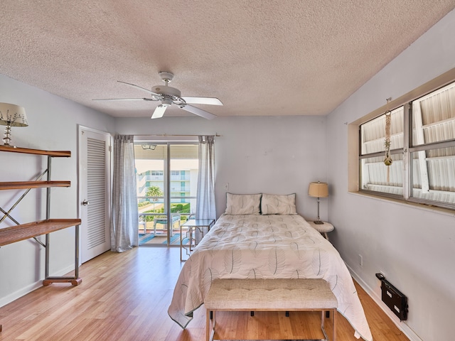 bedroom featuring ceiling fan, light hardwood / wood-style floors, access to outside, and a textured ceiling