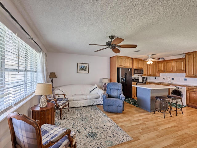 living room with light hardwood / wood-style flooring, washer / clothes dryer, a textured ceiling, and ceiling fan