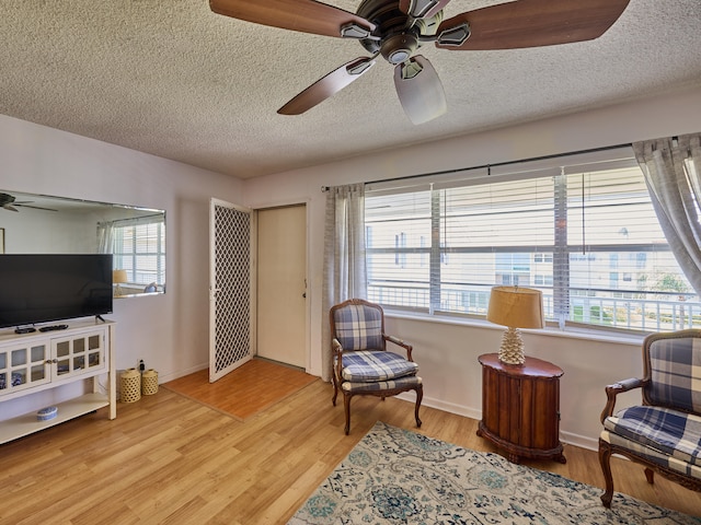 sitting room with light hardwood / wood-style floors, a textured ceiling, and ceiling fan