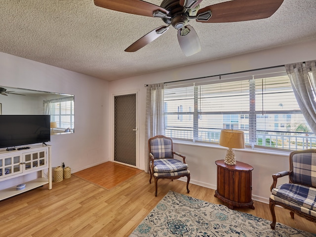 sitting room with light hardwood / wood-style floors, a textured ceiling, and ceiling fan