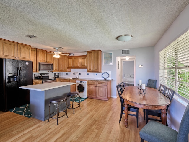 kitchen featuring washer / dryer, sink, light hardwood / wood-style flooring, and stainless steel appliances