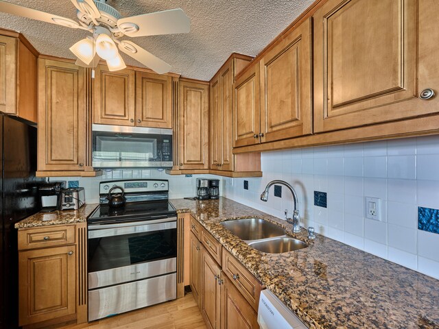 kitchen featuring tasteful backsplash, ceiling fan, stainless steel appliances, sink, and light hardwood / wood-style flooring