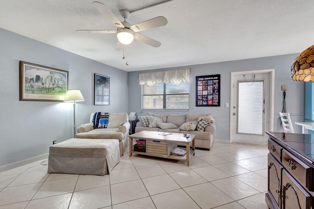 living room with ceiling fan, light tile patterned floors, and a textured ceiling