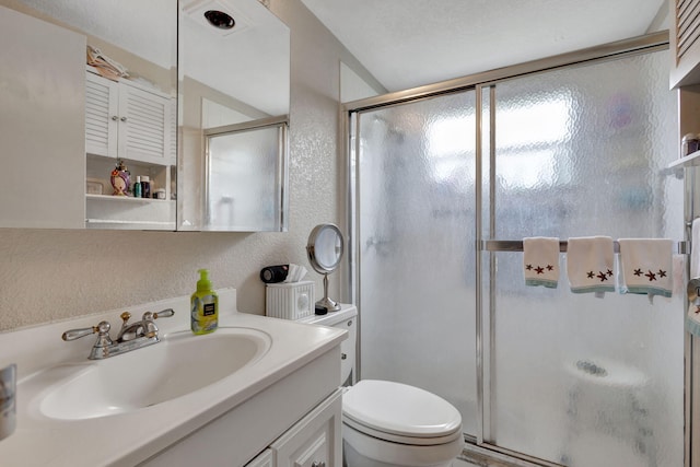 bathroom with toilet, a shower with door, and vanity