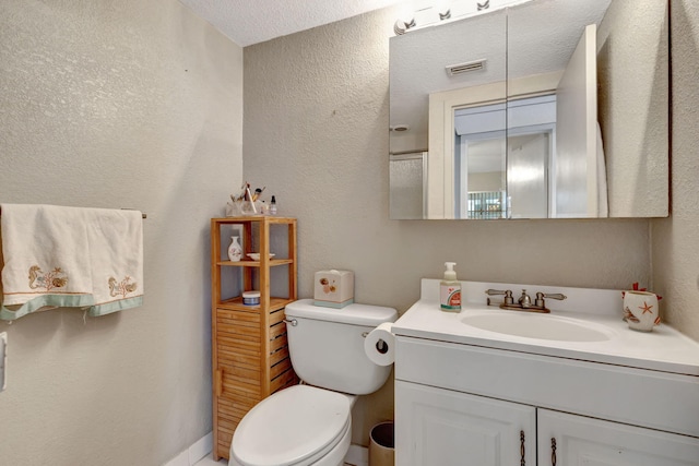 bathroom featuring vanity, toilet, and a textured ceiling