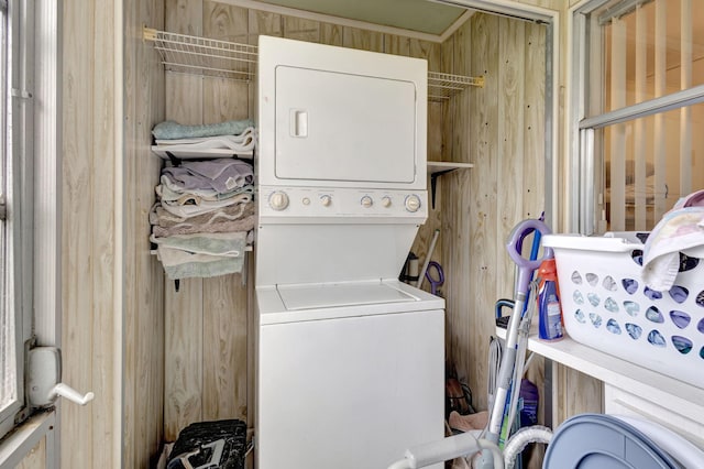 washroom with wooden walls and stacked washer and clothes dryer