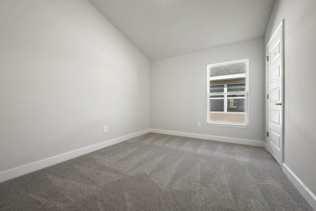 carpeted spare room with vaulted ceiling