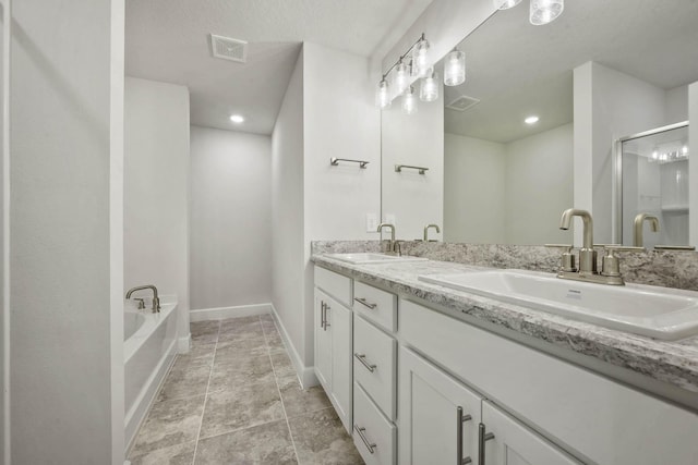 bathroom with a bathing tub, vanity, and a textured ceiling