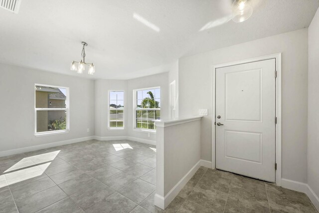 entryway with light tile patterned floors and a chandelier