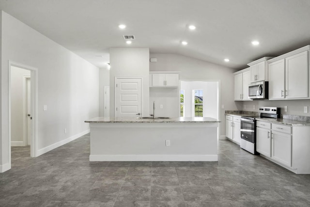 kitchen with white cabinets, stainless steel appliances, a kitchen island with sink, and vaulted ceiling