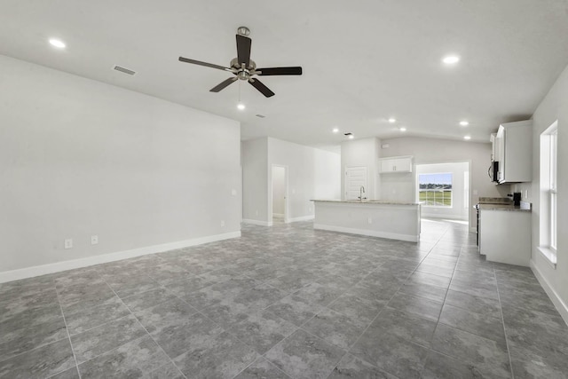 unfurnished living room featuring ceiling fan, sink, dark tile patterned flooring, and lofted ceiling