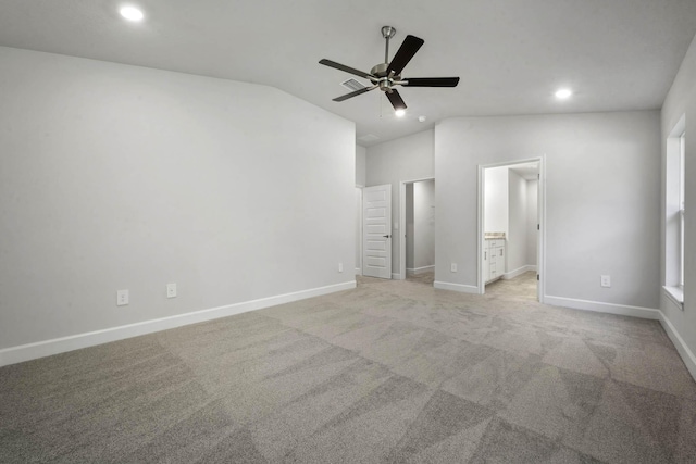 unfurnished bedroom featuring ceiling fan, light colored carpet, connected bathroom, and vaulted ceiling