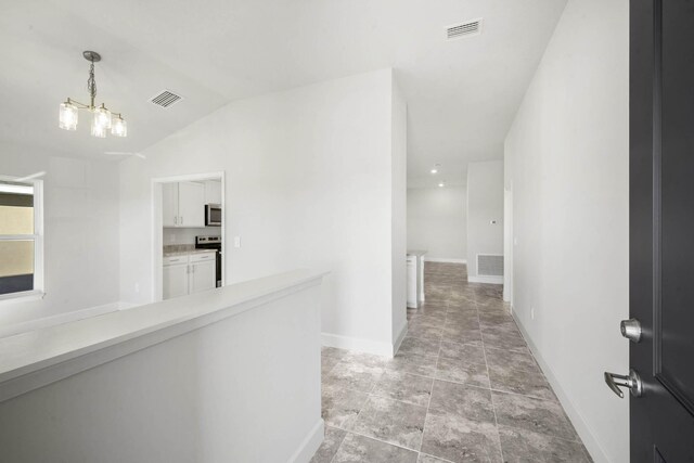 hallway with a chandelier and vaulted ceiling