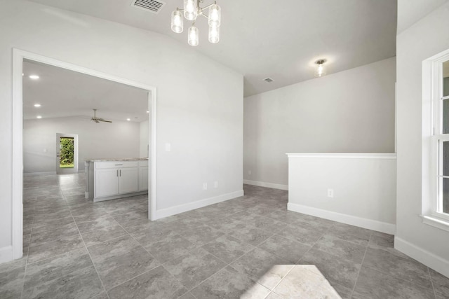 empty room with ceiling fan with notable chandelier and lofted ceiling