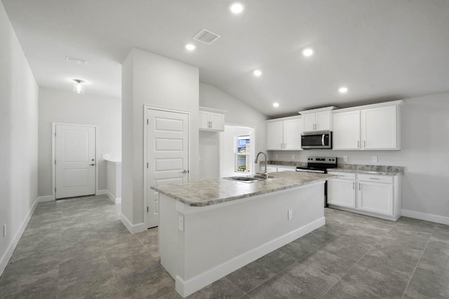 kitchen featuring appliances with stainless steel finishes, vaulted ceiling, sink, a center island with sink, and white cabinets