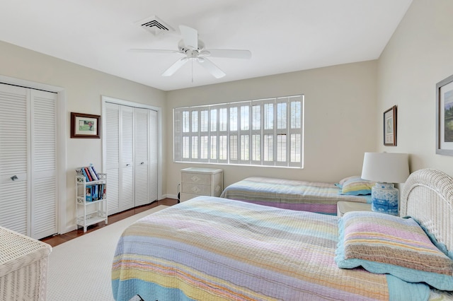 bedroom featuring multiple closets, ceiling fan, and wood-type flooring