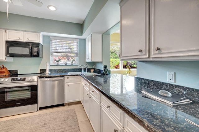 kitchen featuring white cabinetry, appliances with stainless steel finishes, light tile patterned floors, and dark stone countertops