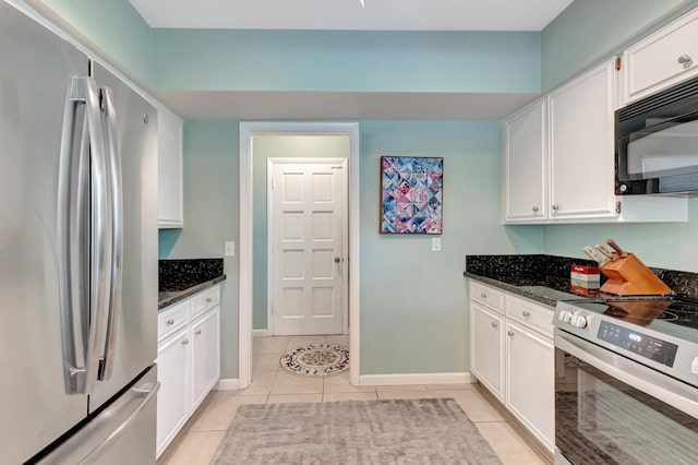 kitchen featuring stainless steel appliances, dark stone countertops, white cabinets, and light tile patterned floors