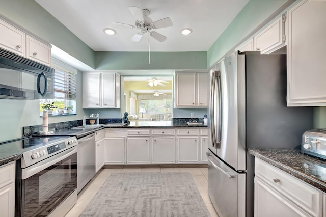 kitchen featuring light tile patterned floors, appliances with stainless steel finishes, ceiling fan, dark stone counters, and white cabinets