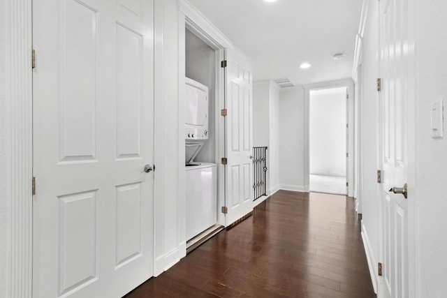 hallway with dark hardwood / wood-style floors and stacked washer and clothes dryer