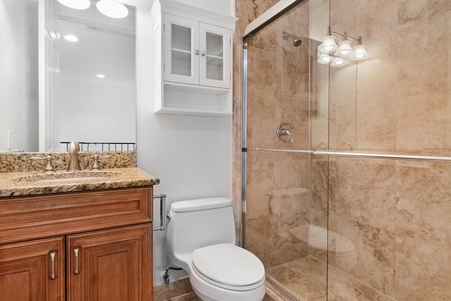 bathroom featuring toilet, a shower with door, and vanity