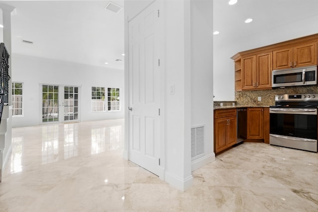 kitchen featuring stainless steel appliances, french doors, light stone countertops, and tasteful backsplash