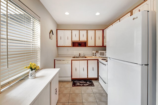 kitchen with white cabinetry, sink, white appliances, and light tile patterned floors