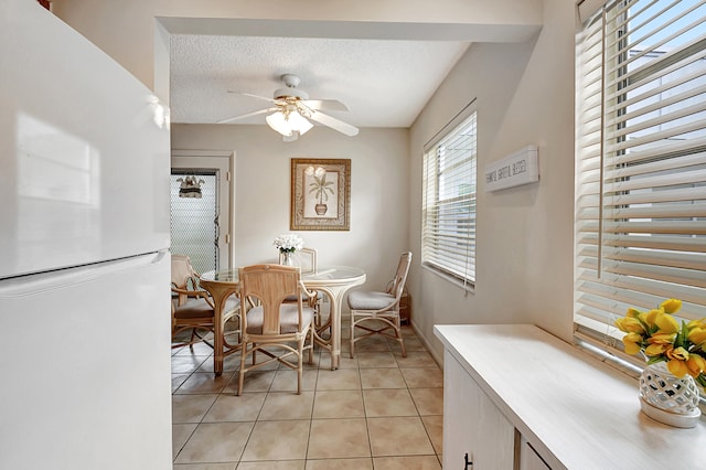 dining area featuring a textured ceiling, ceiling fan, and light tile patterned floors