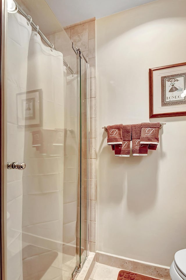 bathroom with tile patterned floors, walk in shower, and toilet