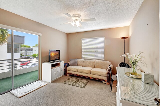 living room featuring a textured ceiling, ceiling fan, and light colored carpet