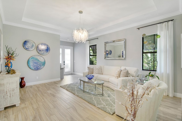 living room featuring a tray ceiling, crown molding, light hardwood / wood-style flooring, and a chandelier