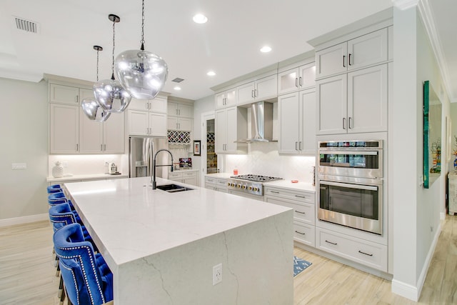 kitchen featuring wall chimney exhaust hood, appliances with stainless steel finishes, light hardwood / wood-style floors, sink, and ornamental molding