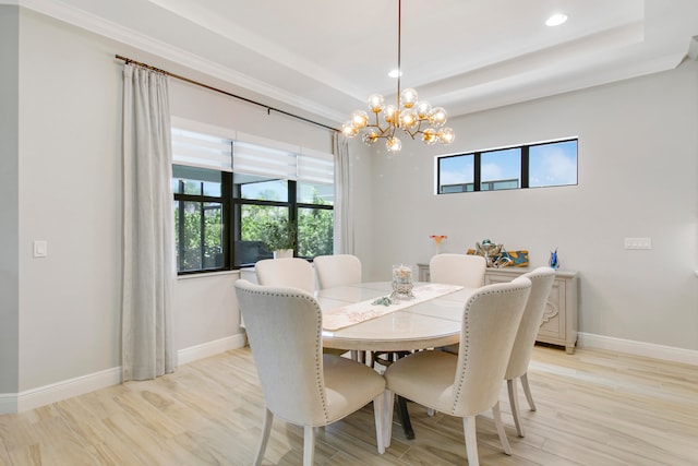 dining area with light hardwood / wood-style flooring, an inviting chandelier, and a tray ceiling