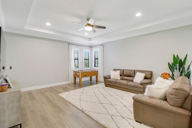 living room featuring light wood-type flooring, a tray ceiling, and ceiling fan