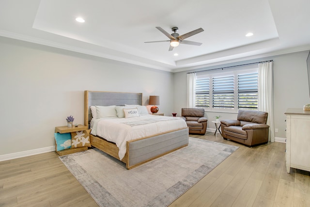 bedroom with a raised ceiling, ceiling fan, ornamental molding, and light wood-type flooring