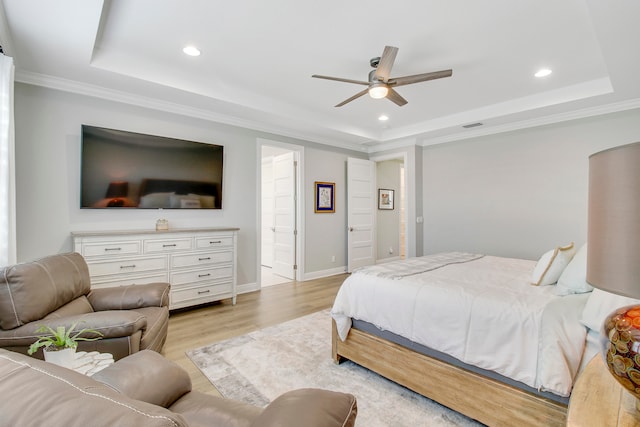 bedroom featuring light wood-type flooring, crown molding, a tray ceiling, and ceiling fan