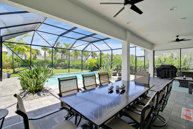 view of patio with glass enclosure, area for grilling, and ceiling fan