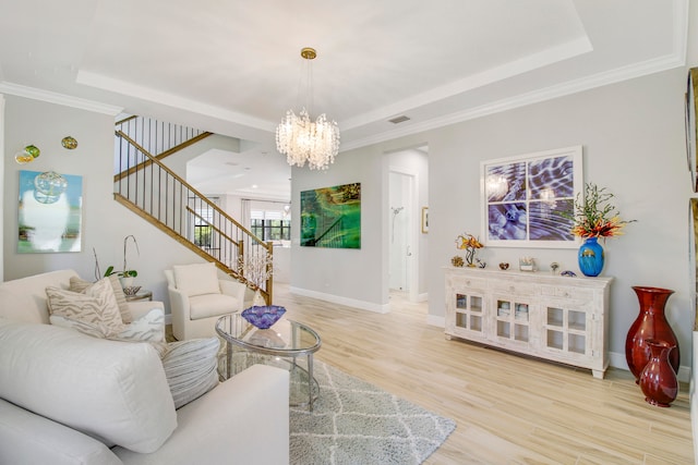 living room featuring a raised ceiling, a notable chandelier, and light wood-type flooring