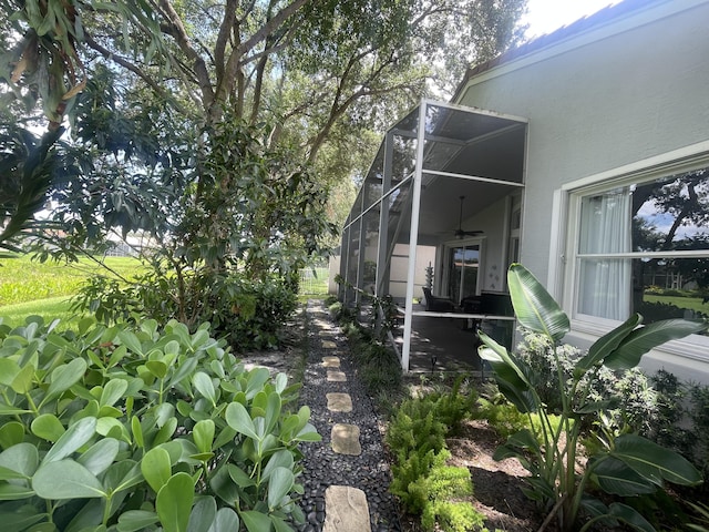 view of yard with a ceiling fan and glass enclosure